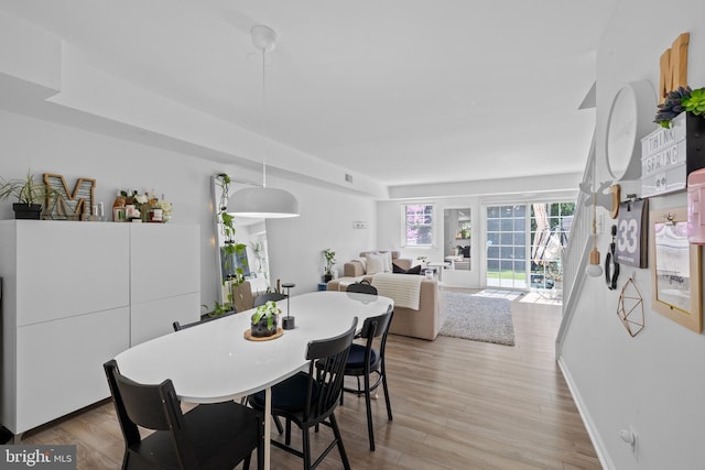 dining room with baseboards, visible vents, and light wood finished floors
