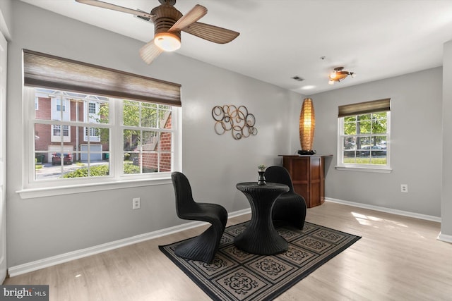 living area featuring baseboards, ceiling fan, and wood finished floors