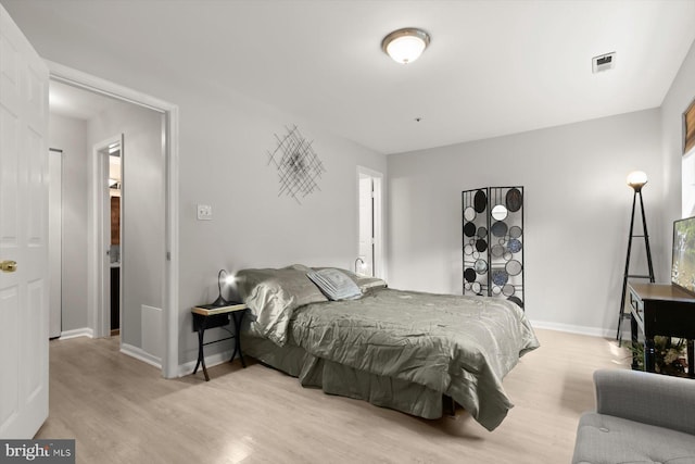 bedroom with baseboards, light wood-style flooring, and visible vents