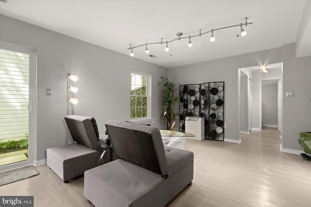 living area featuring light wood-style floors, rail lighting, baseboards, and visible vents