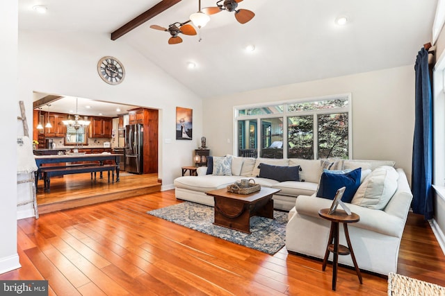 living area with high vaulted ceiling, light wood finished floors, beam ceiling, and ceiling fan with notable chandelier