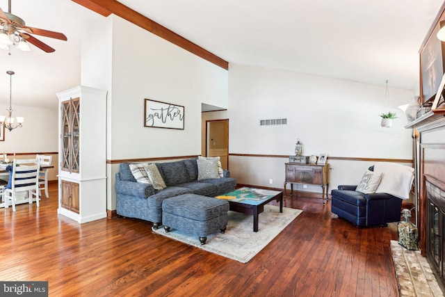 living area with visible vents, wood-type flooring, a brick fireplace, baseboards, and ceiling fan with notable chandelier