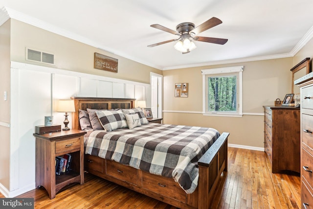 bedroom with crown molding, baseboards, visible vents, and hardwood / wood-style floors