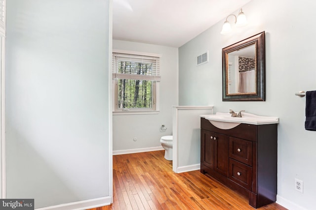 full bathroom featuring visible vents, vanity, baseboards, wood-type flooring, and toilet