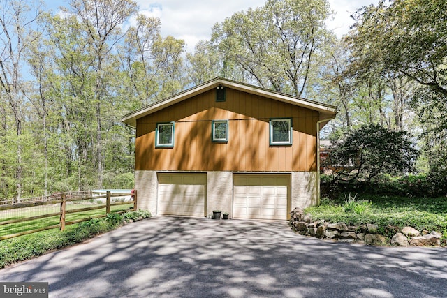 view of side of home featuring fence, driveway, and a garage