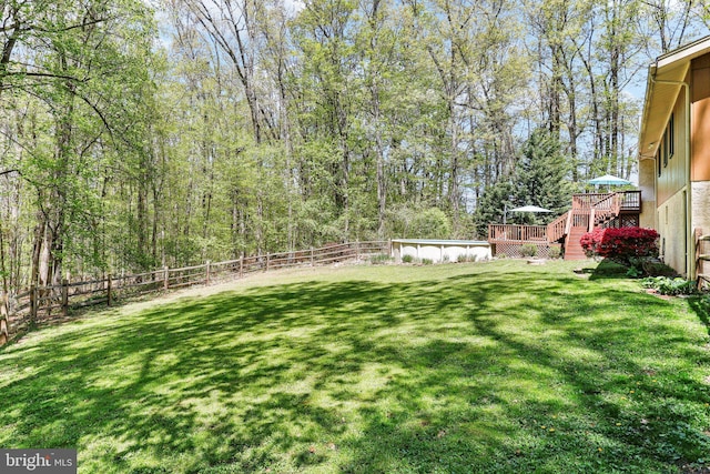 view of yard with a fenced backyard, a wooden deck, and stairs