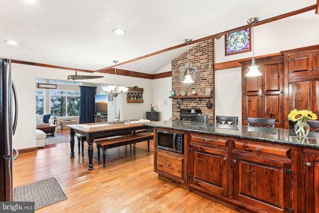kitchen with vaulted ceiling, light wood-type flooring, a chandelier, stainless steel appliances, and open floor plan