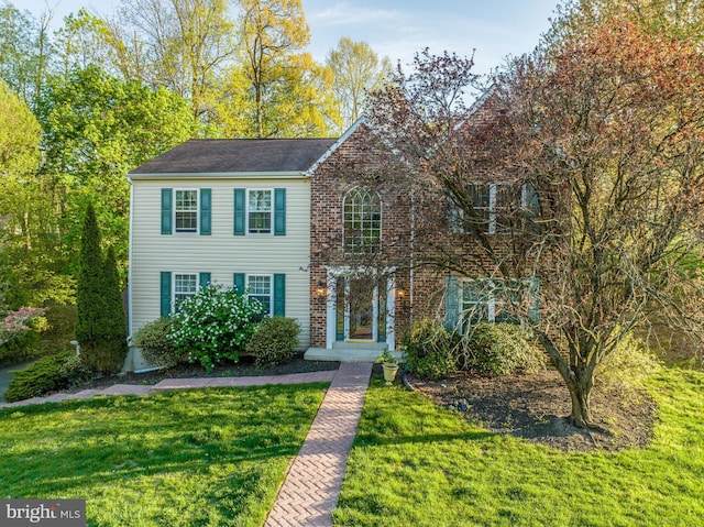 colonial-style house featuring a front yard and brick siding