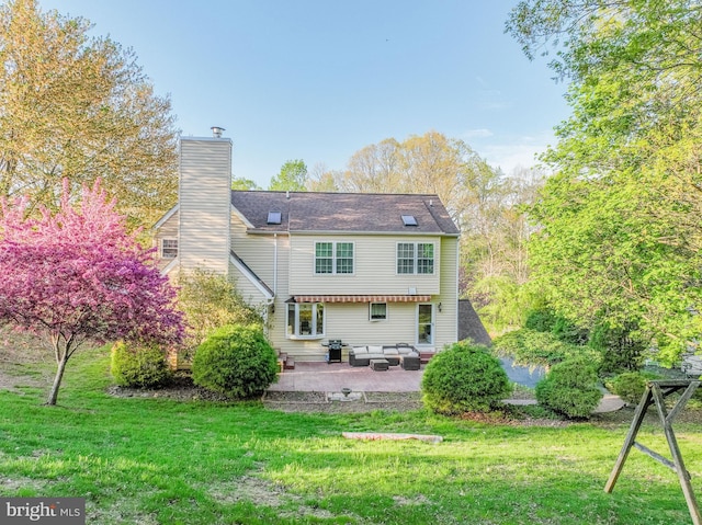 rear view of house featuring a chimney, an outdoor living space, a yard, and a patio area