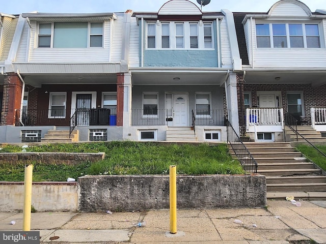 multi unit property featuring a porch, brick siding, and stairway