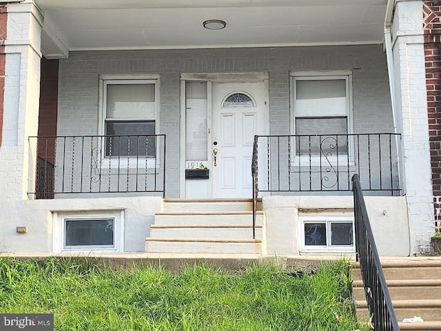 property entrance featuring covered porch and brick siding