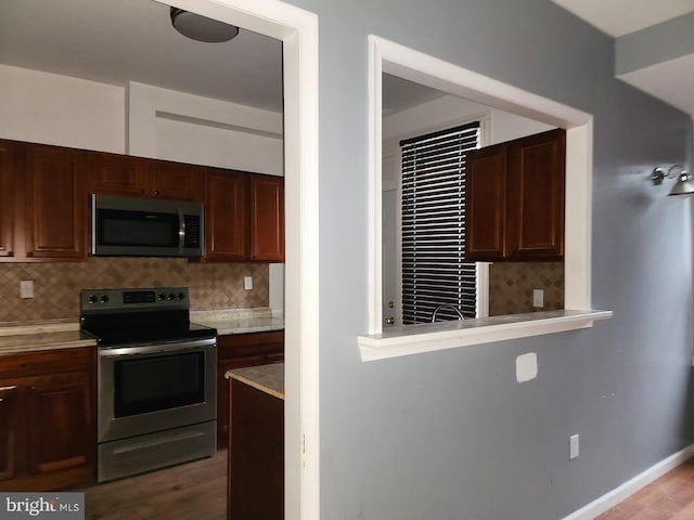kitchen featuring light countertops, wood finished floors, tasteful backsplash, and stainless steel appliances