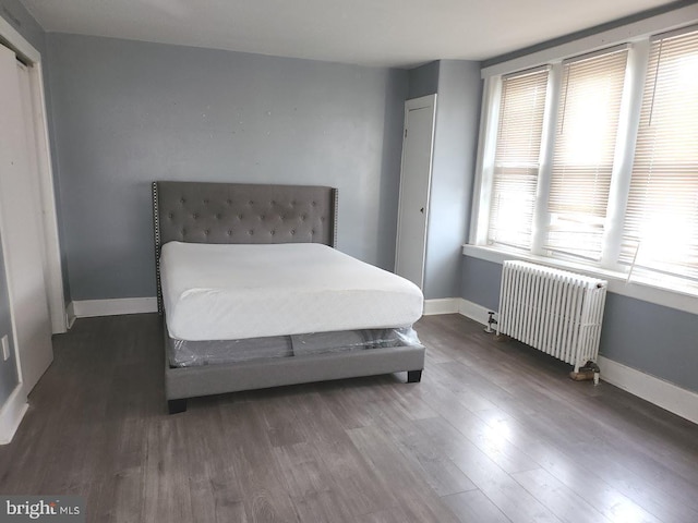 bedroom featuring baseboards, wood finished floors, and radiator