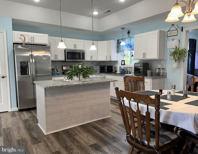 kitchen with visible vents, appliances with stainless steel finishes, light stone counters, white cabinetry, and dark wood-type flooring