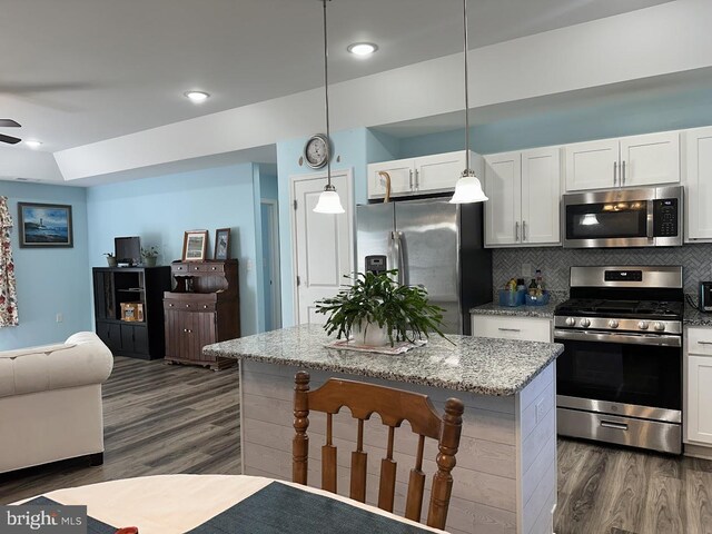 kitchen featuring stainless steel appliances, open floor plan, white cabinetry, decorative backsplash, and dark wood-style floors