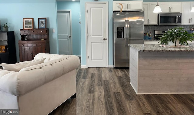 kitchen featuring light stone countertops, dark wood-type flooring, white cabinetry, appliances with stainless steel finishes, and backsplash
