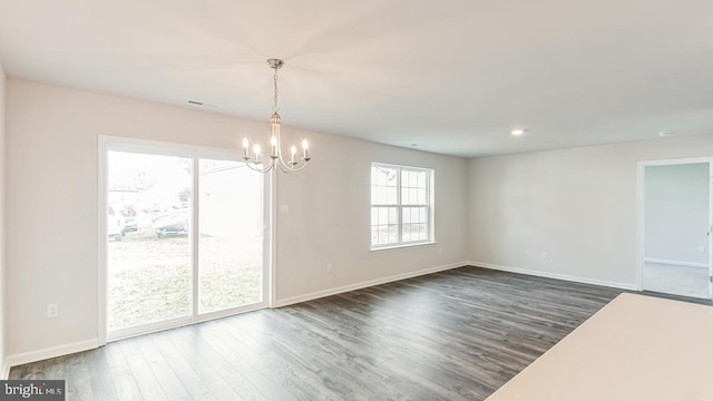 unfurnished dining area with dark wood finished floors, baseboards, visible vents, and an inviting chandelier