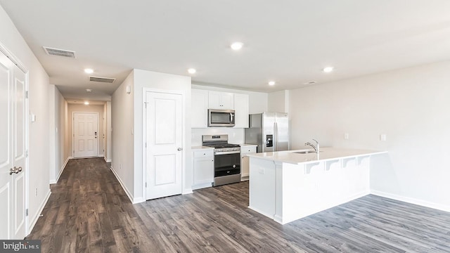 kitchen featuring stainless steel appliances, light countertops, a peninsula, and dark wood-type flooring