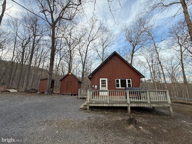 back of property featuring a deck, an outbuilding, and a shed