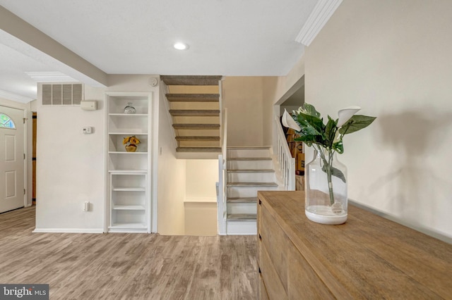 interior space with stairs, ornamental molding, and wood finished floors