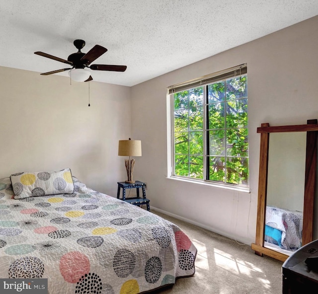 carpeted bedroom with a ceiling fan, a textured ceiling, and baseboards