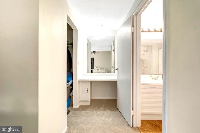 corridor with carpet floors, a sink, and baseboards