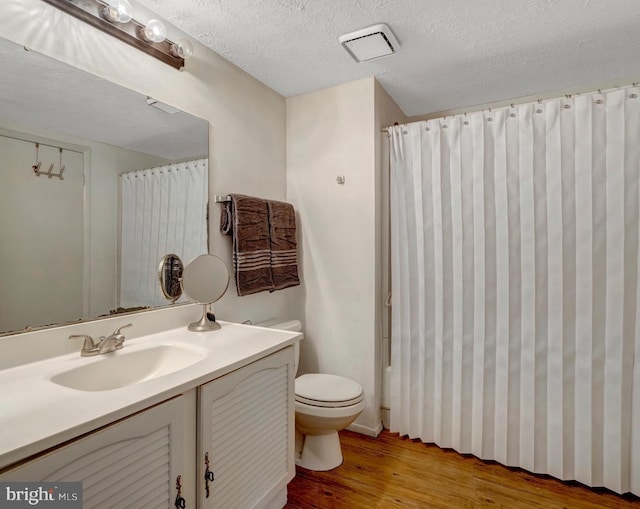bathroom with vanity, a textured ceiling, toilet, and wood finished floors