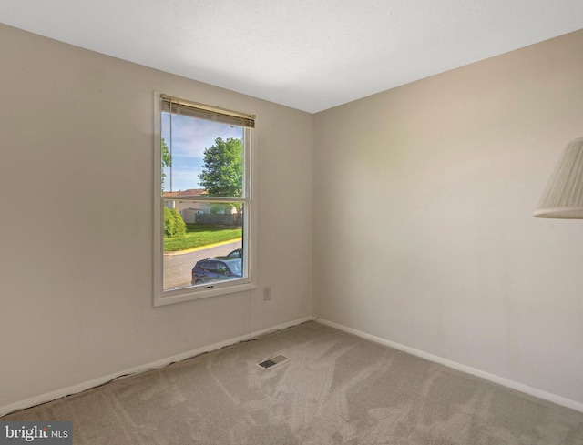 carpeted spare room with visible vents and baseboards