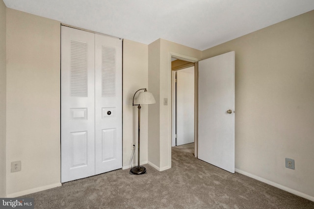 unfurnished bedroom with carpet flooring, baseboards, and a closet