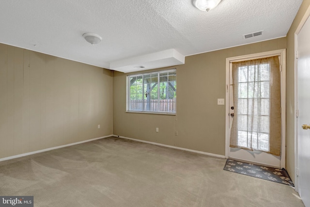 doorway to outside with carpet floors, a textured ceiling, baseboards, and visible vents
