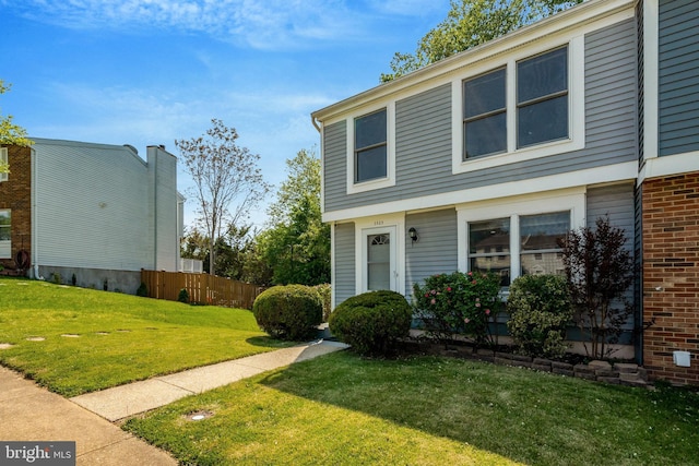 view of front of house featuring brick siding, fence, and a front yard