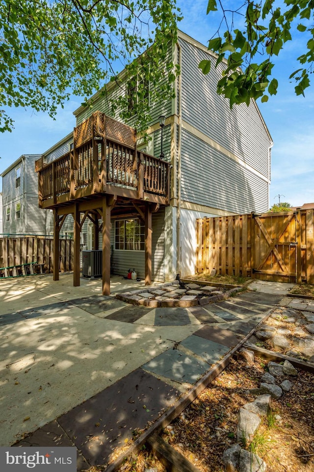 rear view of house featuring a deck, fence, a gate, and a patio