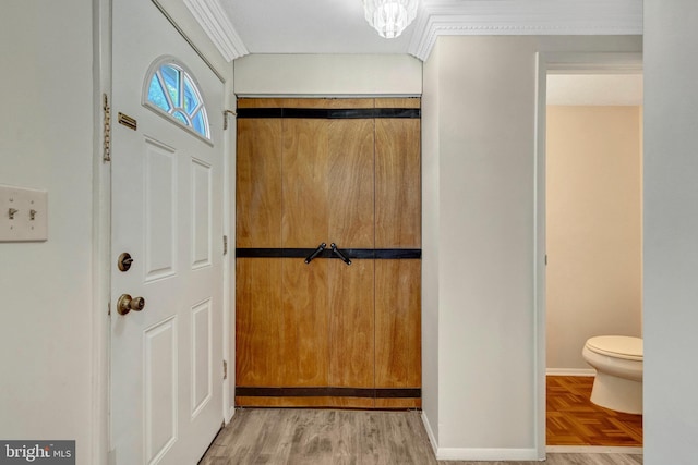 foyer entrance with crown molding, baseboards, and parquet floors