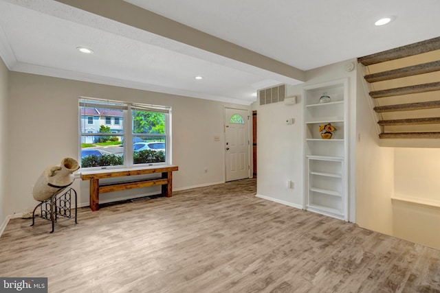 living area featuring crown molding, baseboards, wood finished floors, and visible vents