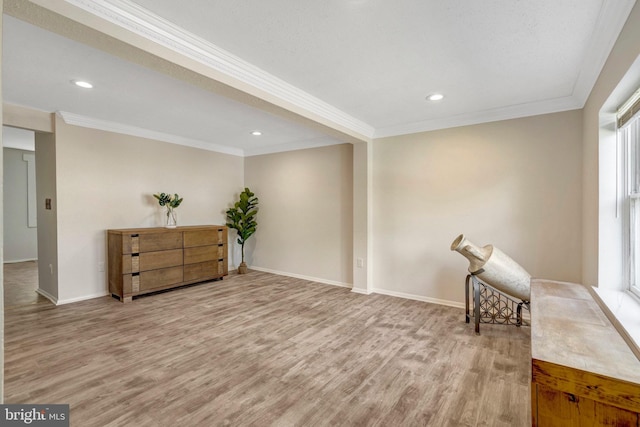 living area featuring crown molding, baseboards, a wealth of natural light, and light wood finished floors