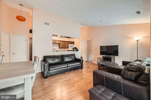 1317 Greenbriar Cir Unit 7-1317, Pikesville, MD 21208 - living room with high vaulted ceiling, light wood-type flooring, a textured ceiling, and baseboards