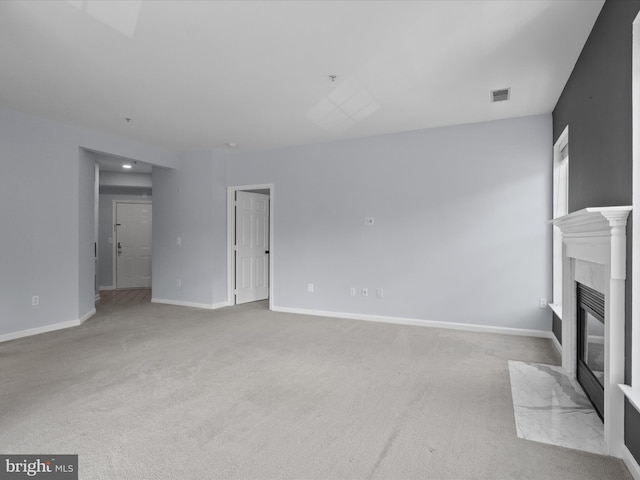 unfurnished living room featuring visible vents, carpet flooring, baseboards, and a high end fireplace