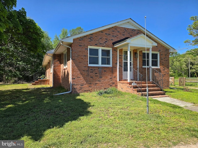 bungalow featuring a front yard and brick siding