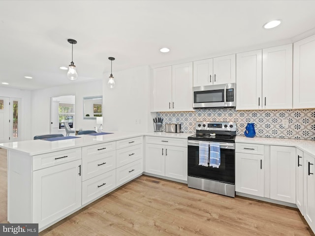 327 Oakwood St, Bethany Beach, DE 19930 - kitchen featuring stainless steel appliances, a peninsula, light countertops, white cabinetry, and light wood-style flooring