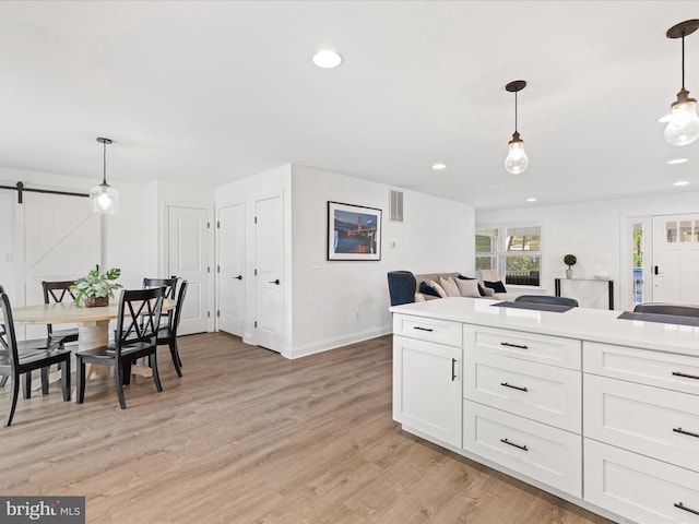 327 Oakwood St, Bethany Beach, DE 19930 - kitchen with baseboards, light wood-style flooring, white cabinetry, a barn door, and hanging light fixtures