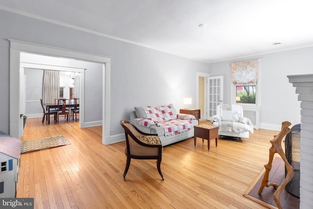 living room featuring ornamental molding, light wood-type flooring, and baseboards