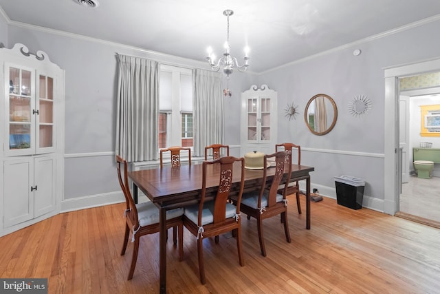 dining area featuring a chandelier, light wood-style floors, baseboards, and crown molding