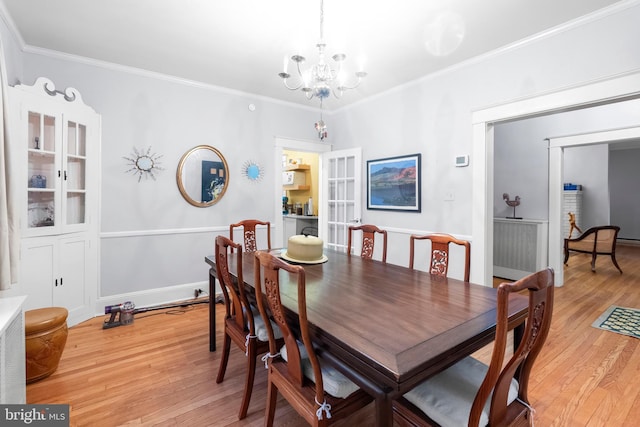 dining space featuring a chandelier, light wood-type flooring, and crown molding