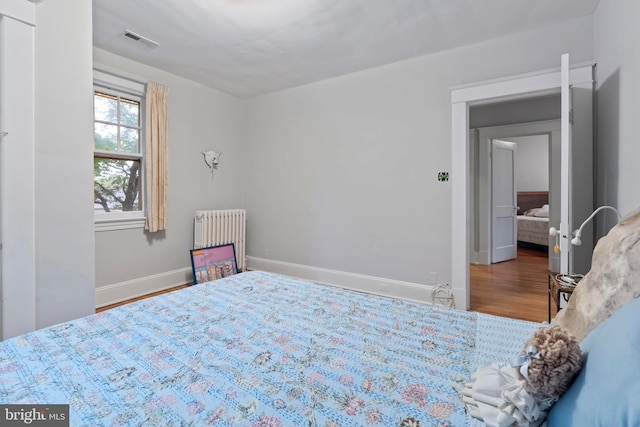 bedroom featuring radiator, baseboards, and wood finished floors
