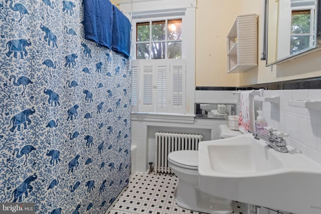 full bathroom with radiator heating unit, tile walls, a sink, toilet, and curtained shower