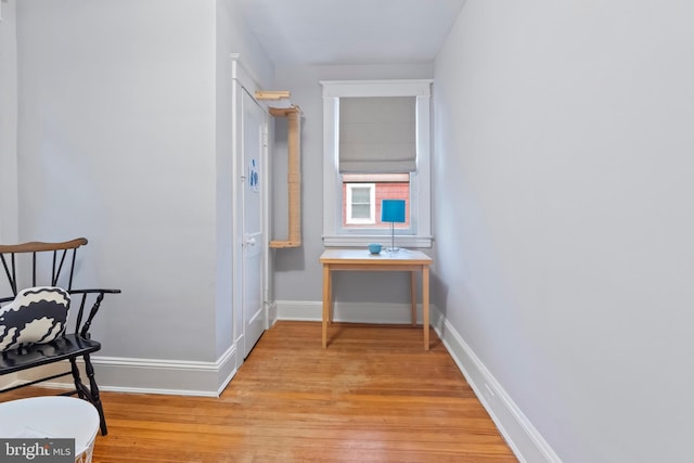 corridor featuring light wood-type flooring and baseboards