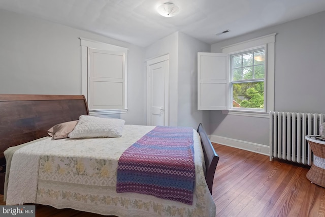 bedroom featuring radiator heating unit, wood finished floors, and baseboards