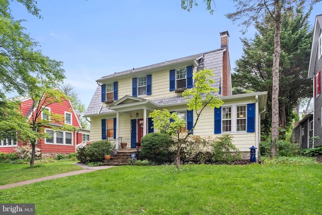 view of front of house with a chimney, a front yard, and covered porch