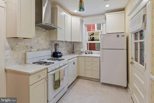 kitchen featuring white appliances, wall chimney range hood, a sink, tasteful backsplash, and recessed lighting