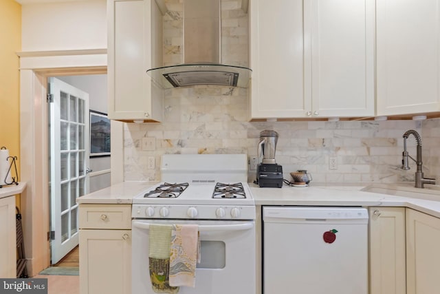 kitchen featuring white appliances, wall chimney exhaust hood, a sink, and tasteful backsplash